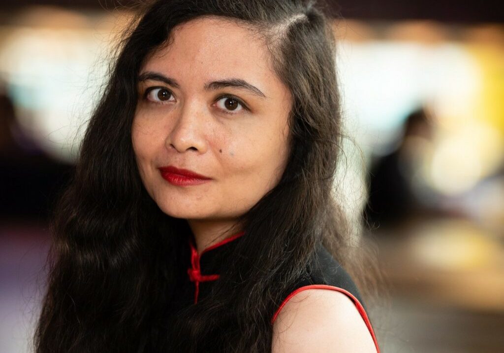 Head and shoulders headshot of a woman with long dark hair